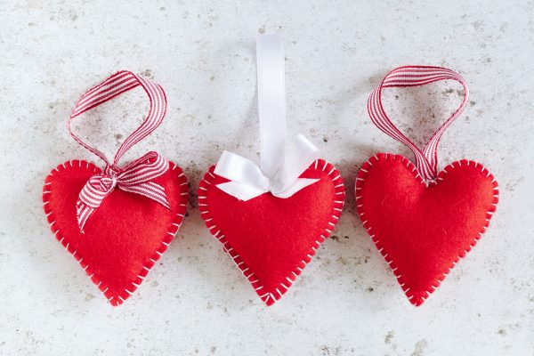 beginners felt hearts sewn with white thread blanket stitch, with candy strip ribbons and bows