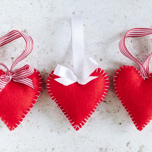 beginners felt hearts sewn with white thread blanket stitch, with candy strip ribbons and bows