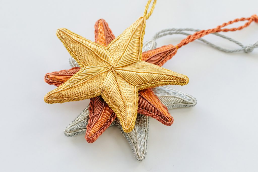 three stacked goldwork stars the top in gold, second in copper and base in silver